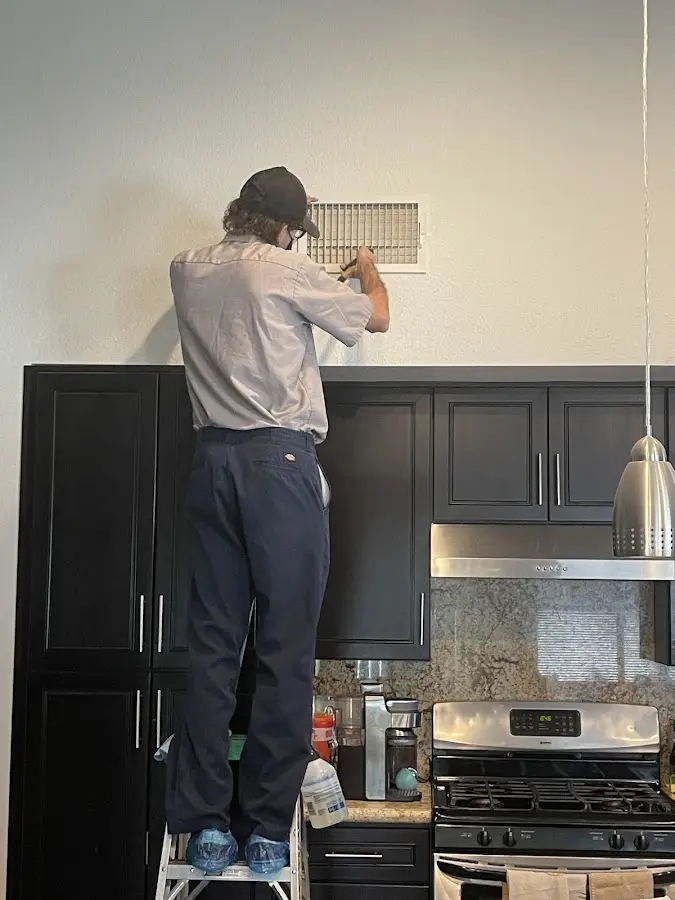 Technician inspecting an air vent during HVAC service in Darby